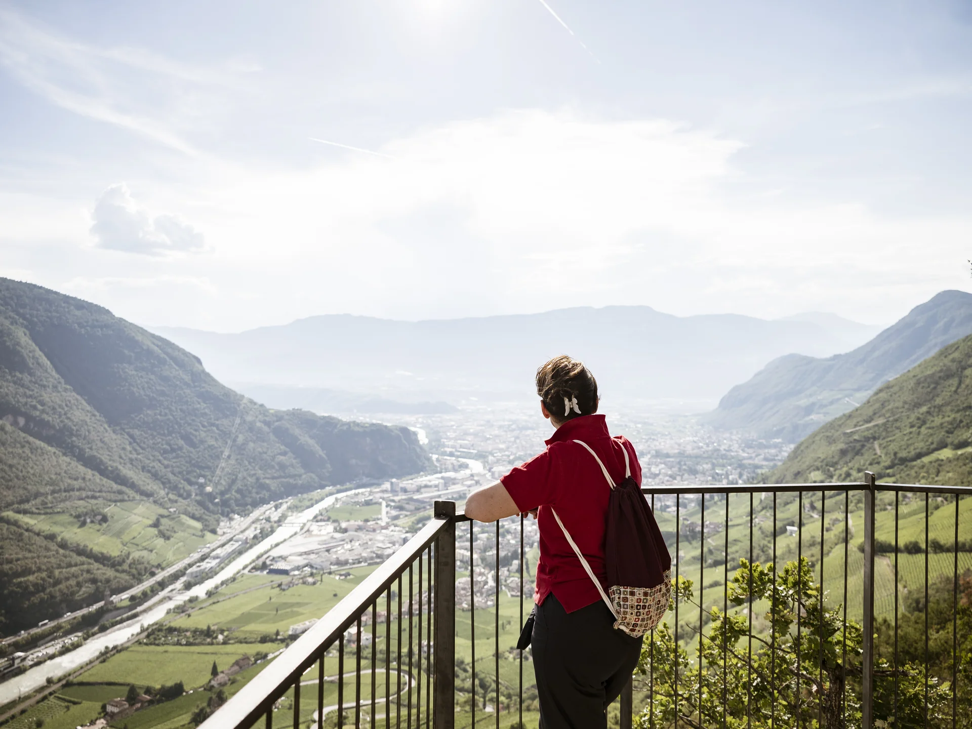 Urlaub am Ritten: die Insider-Tipps des Armonia Wanderin blickt von einem Aussichtspunkt über ein Tal zwischen bewaldeten Bergen
