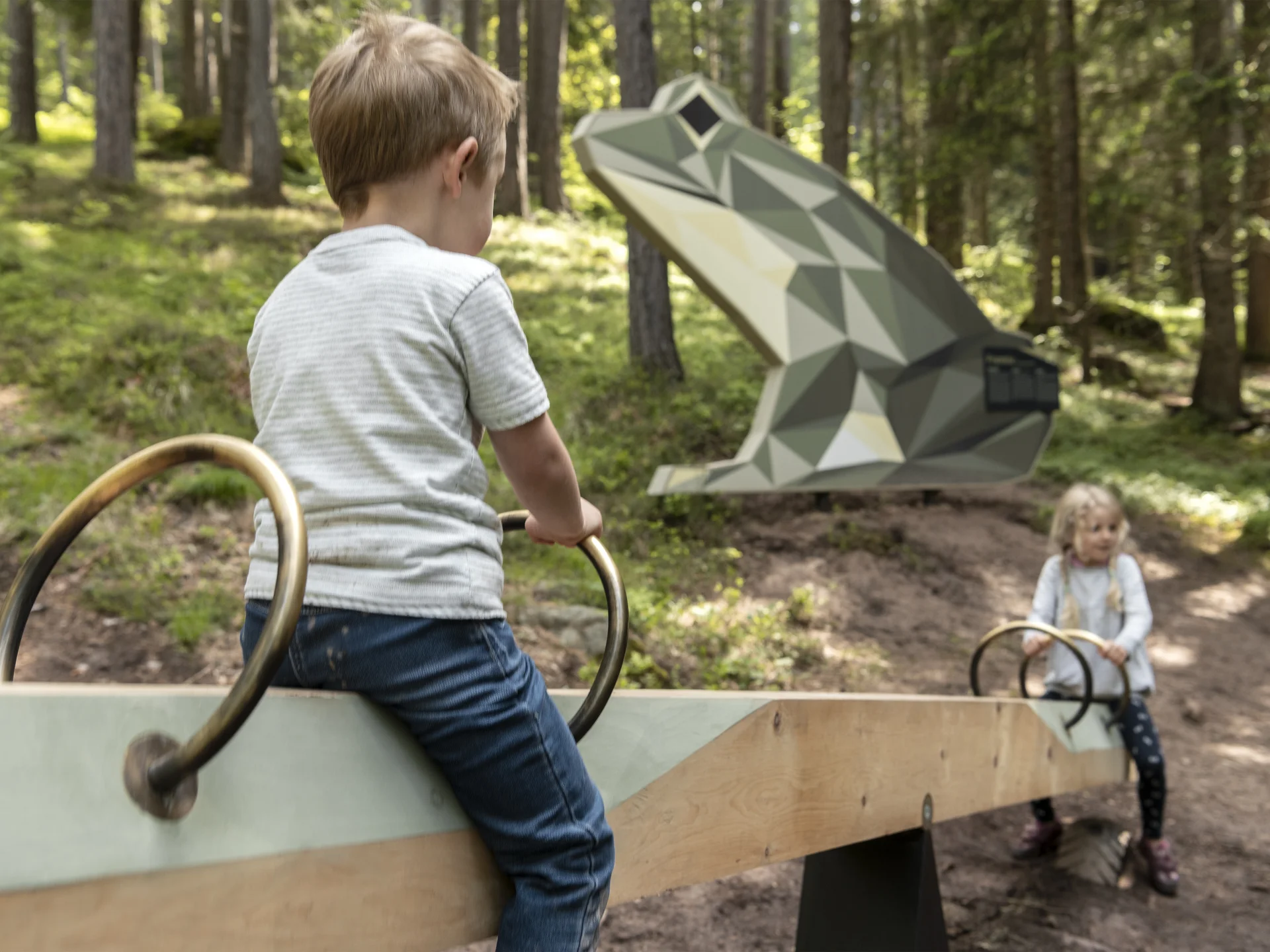 Urlaub am Ritten: die Insider-Tipps des Armonia Zwei Kinder spielen auf einer Wippe im Wald vor einer geometrischen Skulptur