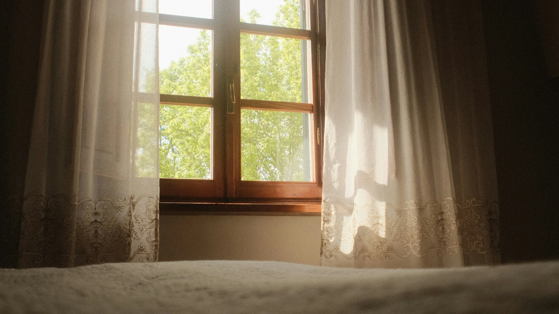 Ferienwohnung am Ritten: Armonia, Hof mit Musik Sonnenlicht fällt durch ein Fenster mit hellen Vorhängen auf das Bett