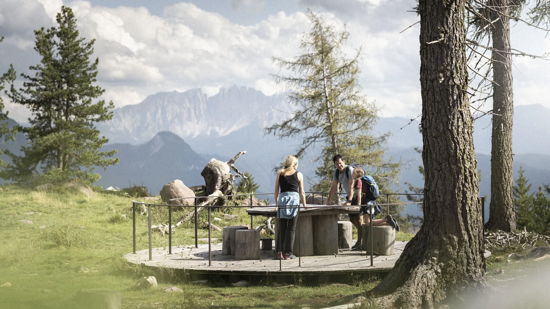 Bilder vom Armonia: Hof am Ritten in Südtirol Wanderer machen Rast an einem Tisch auf einer Holzplattform mit Bergblick