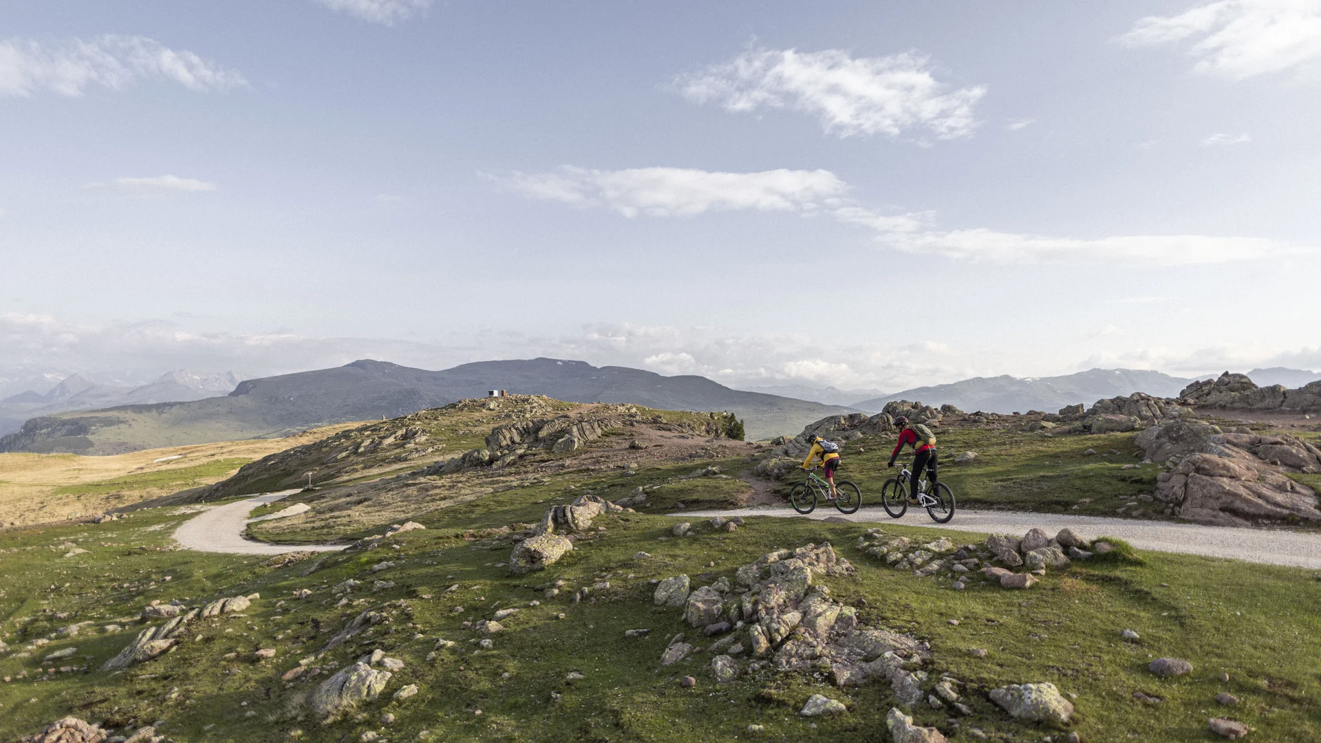 Bilder vom Armonia: Hof am Ritten in Südtirol Zwei Mountainbiker fahren auf einem felsigen Weg durch eine offene Berglandschaft