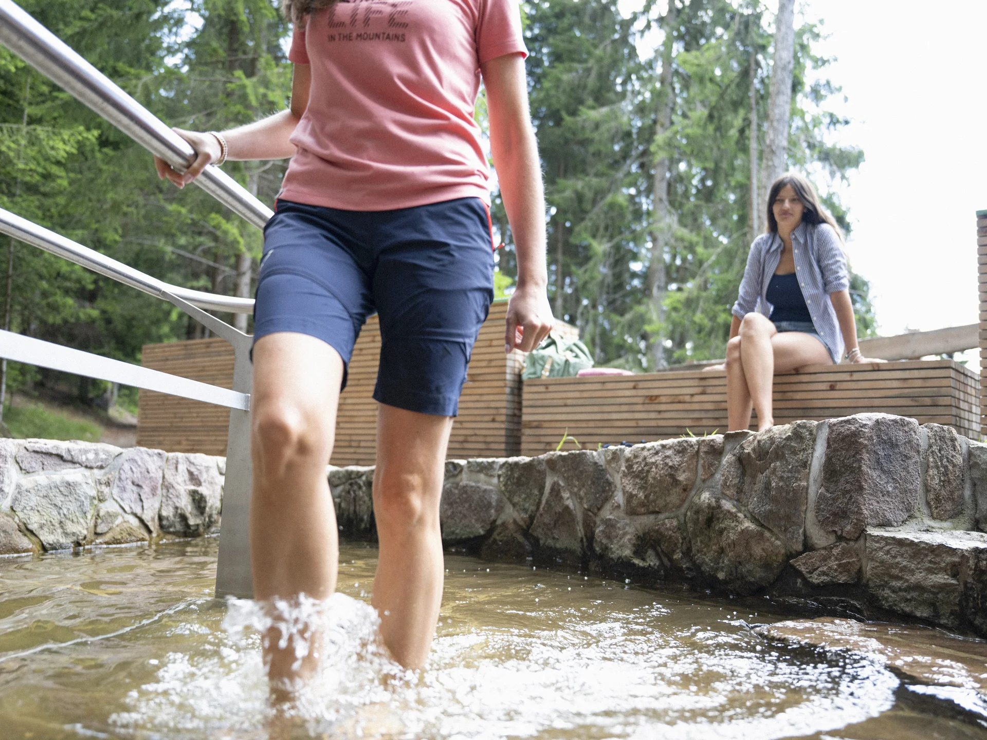 Urlaub am Ritten: die Insider-Tipps des Armonia Mann watet durch ein flaches Wasserbecken, während eine Frau am steinernen Rand sitzt