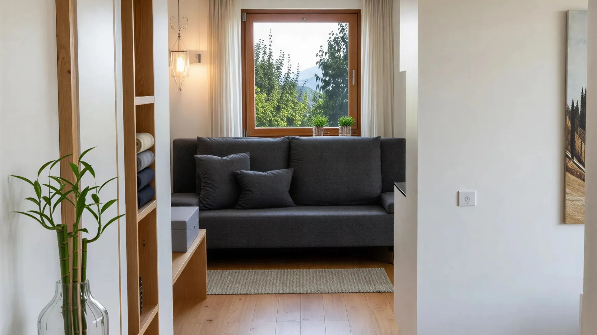 Bilder vom Armonia: Hof am Ritten in Südtirol Heller Wohnbereich mit grauem Sofa am Fenster, Holzboden und Pflanze in einer Glasvase