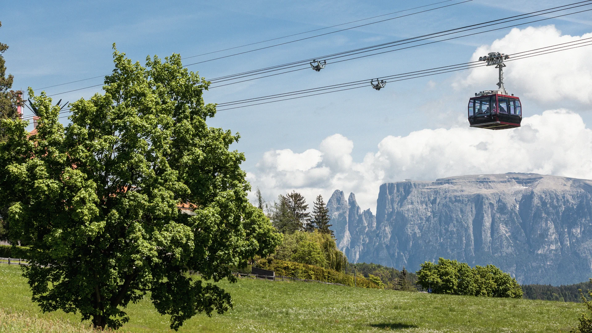 Bilder vom Armonia: Hof am Ritten in Südtirol Seilbahn schwebt über einer grünen Wiese vor einer felsigen Bergkulisse