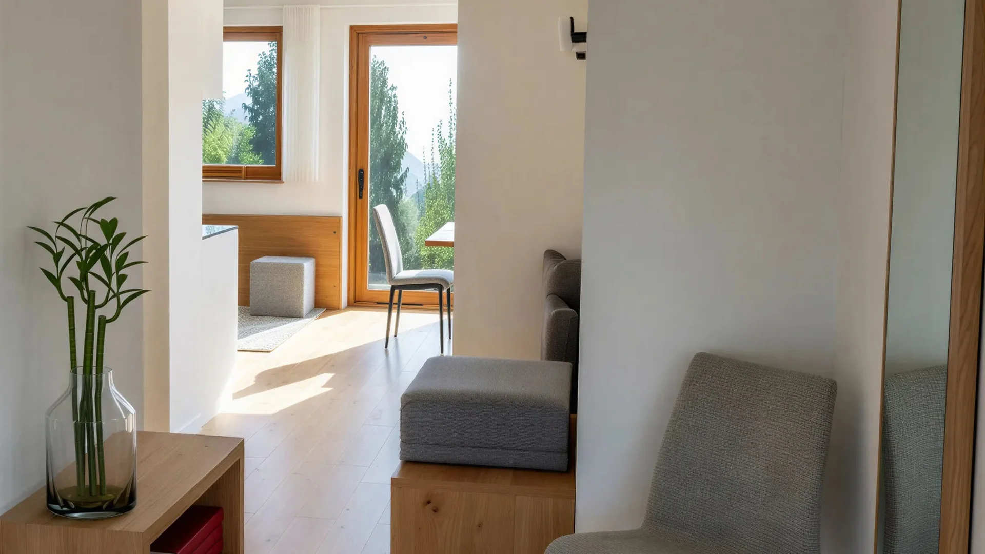 Bilder vom Armonia: Hof am Ritten in Südtirol Heller Wohnungsflur mit grauem Stuhl, großem Spiegel und Blick durch die Tür zum Wohnbereich