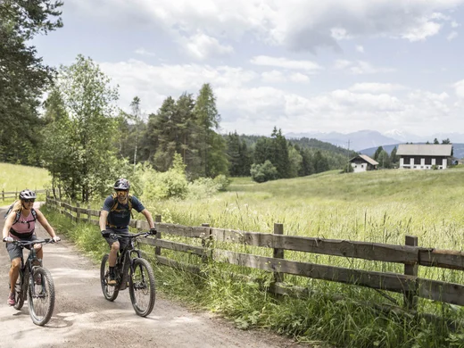Urlaub am Ritten: die Insider-Tipps des Armonia Zwei Radfahrer fahren auf einem Schotterweg durch eine Wiesenlandschaft