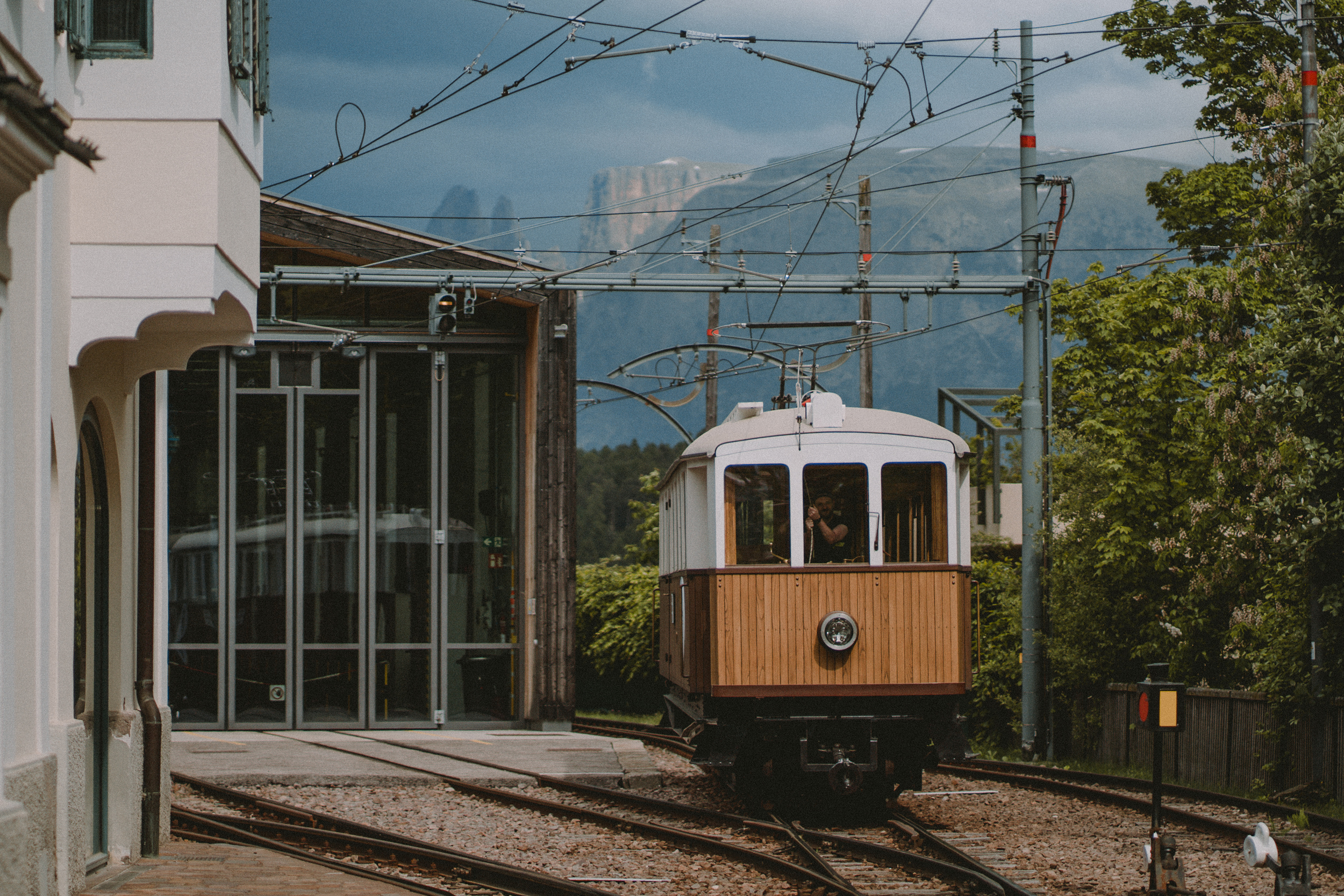 Anreise zum Armonia: Lage am Ritten bei Bozen Historische Bahn mit hölzerner Front an einem Bahnhof vor einer Bergkulisse